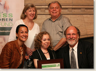 Kelly Rouba, of EAD, after receiving an award for her advocacy from the Catastrophic Illness in Children Relief Fund Commission. On the right of Ms. Rouba is Governor Jon Corzine, of NJ, and on the left is Jennifer Velez, Commissioner of the NJ Dept. of Human Services. Standing are Ms. Rouba's parents Kerry and Frank.
